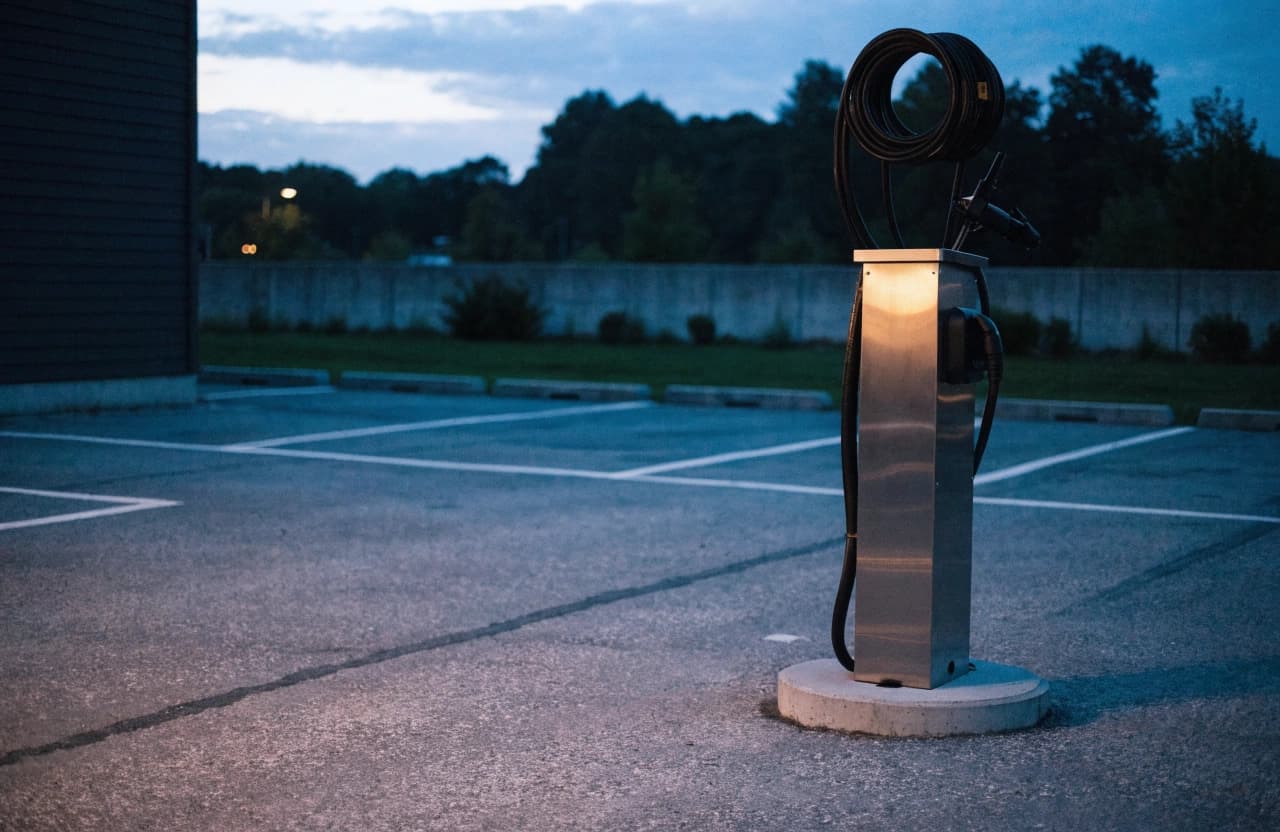 A single AC charging terminal on a base in an empty car park.